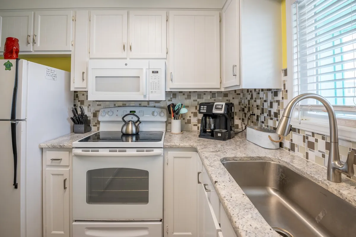 A bright and welcoming kitchen featuring a stove, sink, ample countertop space, and a coffee maker. The scene is set for meal preparation, morning coffee, or gathering with family, reflecting a fully equipped kitchen that encourages self-catering and independence.